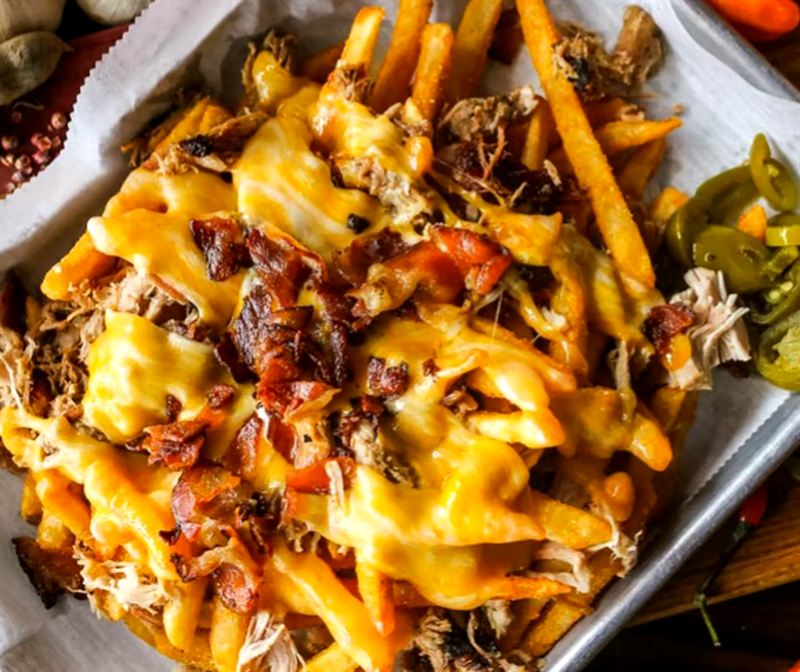 Brisket Piggy Fries smothered in cheese with jalapeños